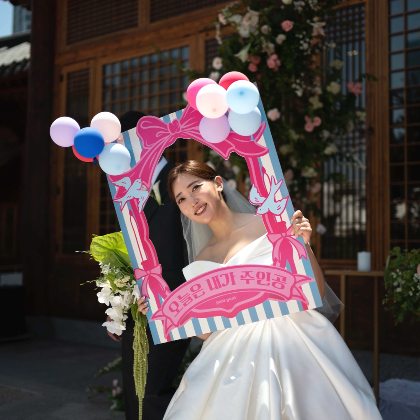 Woman in a wedding dress holding a decorative photo frame with balloons.
it's my day. celebration, birthday