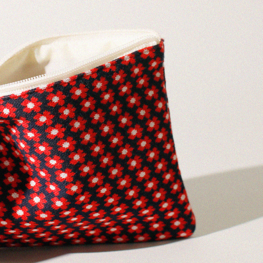 Small pouch with red and white floral pattern on a plain background