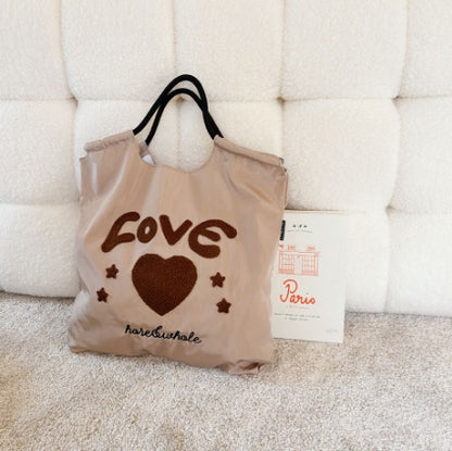 Beige tote bag with 'LOVE' and heart design on a textured surface