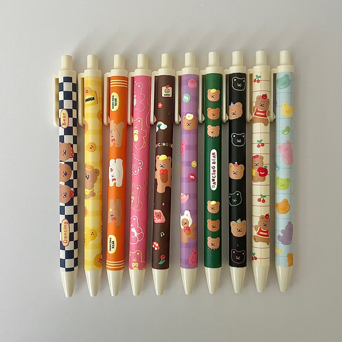 Row of colorful pens with cartoon character designs on a light gray background