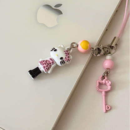 Phone charm with a cat figurine and key-shaped pendant on an Apple device.