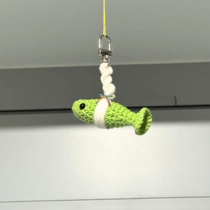 Green fish-shaped toy on a string with beads against a white background