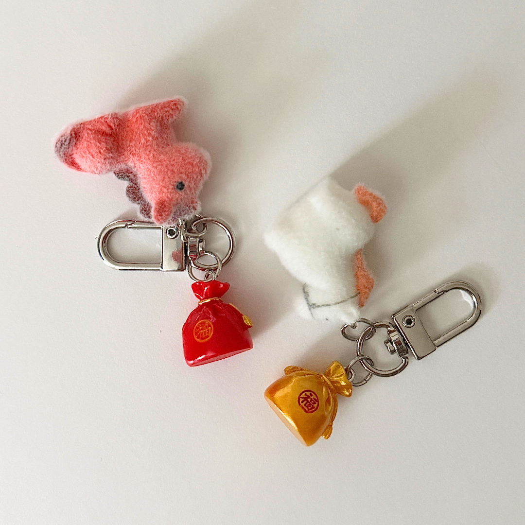 Two keychains with small plush toys attached on a white background