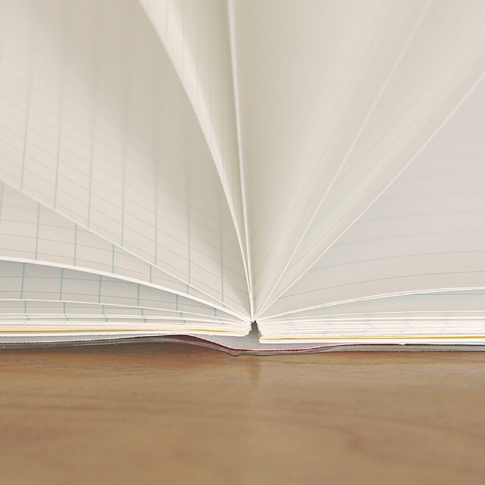 Open book with grid pattern on beige paper on a wooden surface