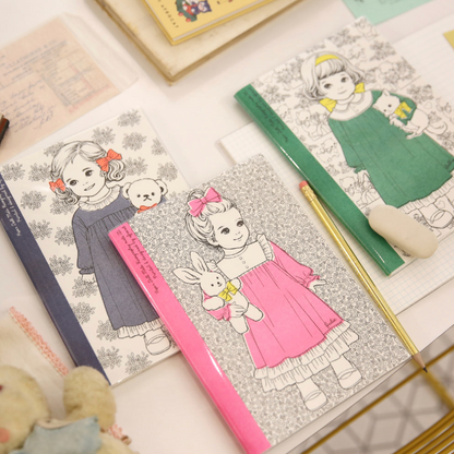 Coloring books with illustrations of children and toys on a table with a cup of coffee.