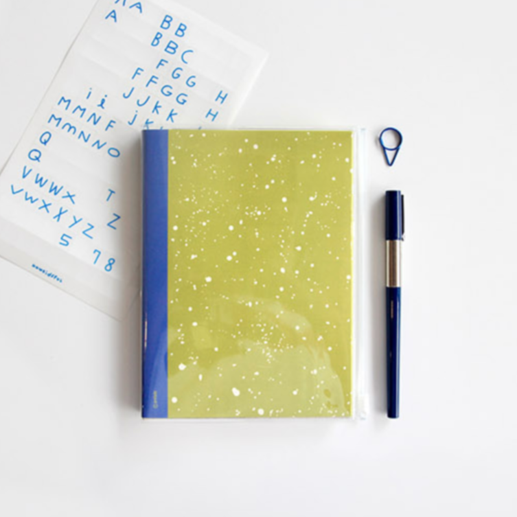 Green notebook with blue accents, pen, and alphabet card on a white background