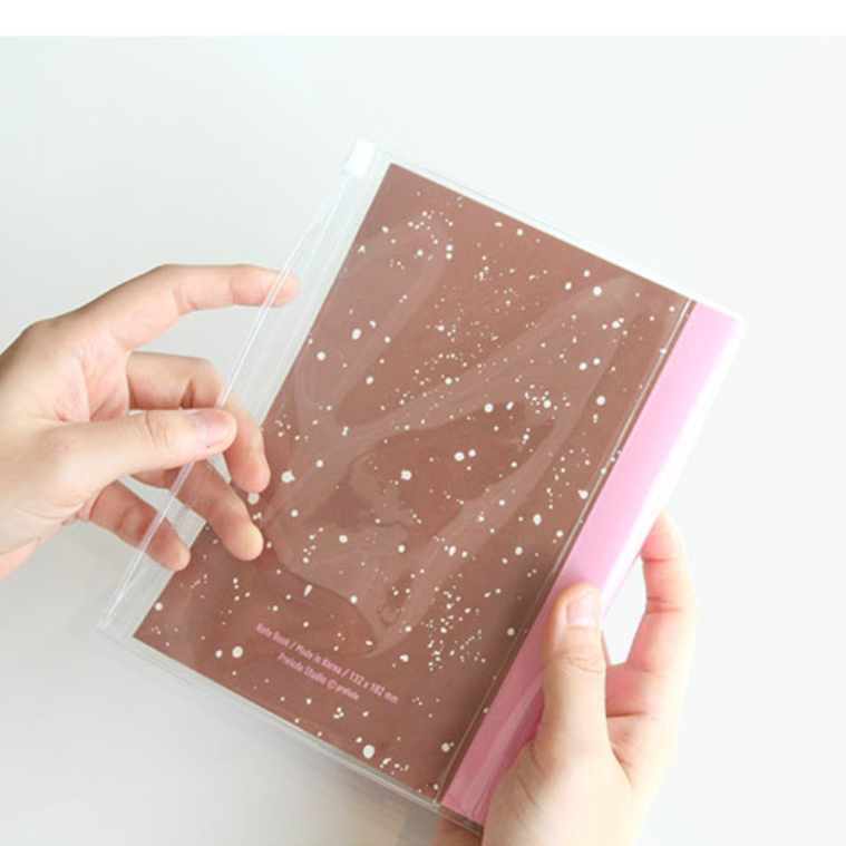 Clear cover being placed on a pink notebook with gold accents.