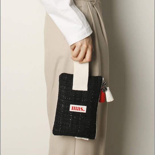 Person holding a black clutch with 'bias' branding against a neutral background