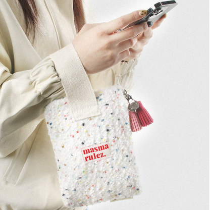 Person holding a small multicolored bag with 'masma rulez' text and a pink tassel.