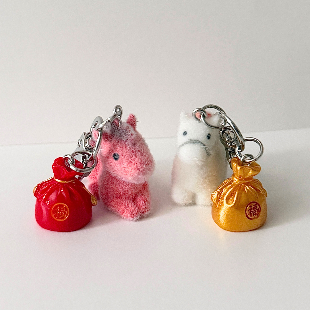 Two plush keychains with red and gold bags on a white background